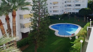 A residential building with a swimming pool surrounded by greenery and palm trees. - BEAUTIFUL APARTMENT NEAR THE BEACH AND THE MOUNTAIN (Benalmádena)