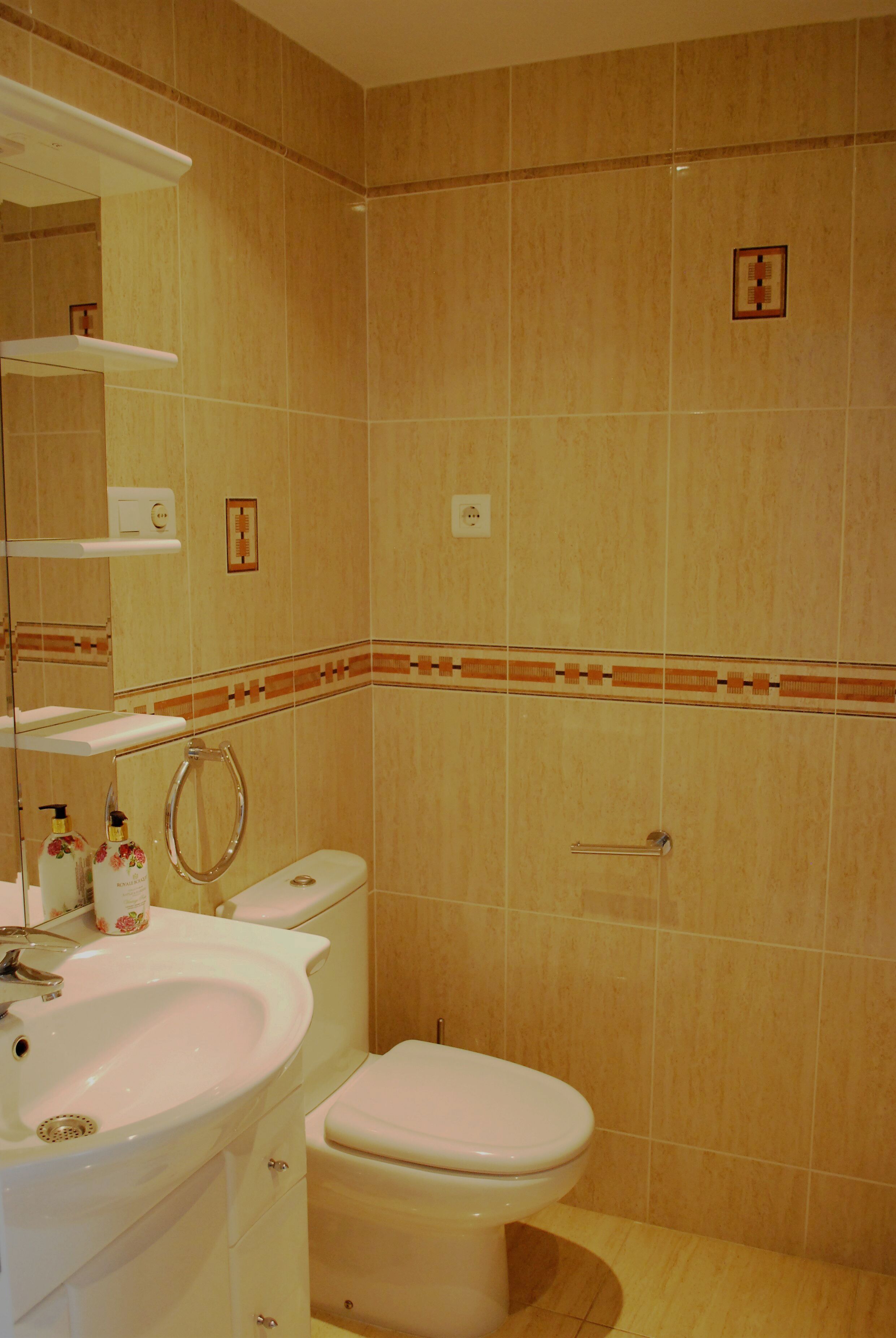 A bathroom with a sink, toilet, and mirror.