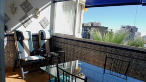 A balcony with a glass table, chairs, and a view of buildings. - BEAUTIFUL APARTMENT NEAR THE BEACH AND THE MOUNTAIN (Benalmádena)