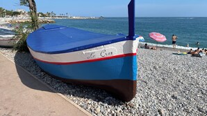 A boat with 'Le Croix' painted on its side, docked on a pebbled beach with a clear view of the sea and a distant shoreline. - Panoramic Sea View - Pool - Quiet (Cagnes-sur-Mer)