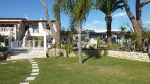 A residential property with a paved driveway, stone walls, and a well-maintained lawn. - Panoramic Sea View - Pool - Quiet (Cagnes-sur-Mer)