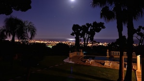 A nighttime view of a cityscape with a prominent moon in the sky, palm trees, and a lit swimming pool area. - Panoramic Sea View - Pool - Quiet (Cagnes-sur-Mer)
