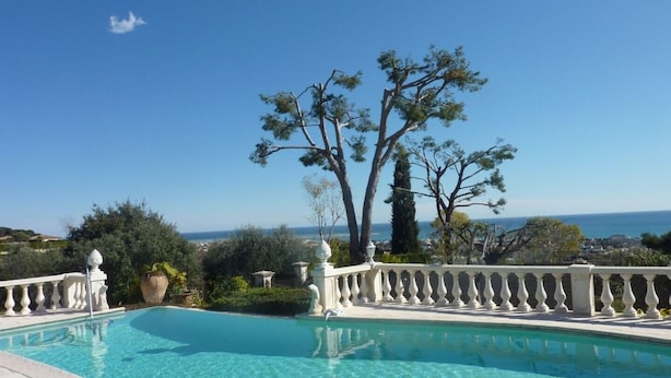 A clear blue swimming pool with a white balustrade, surrounded by trees and a view of the sea. - Panoramic Sea View - Pool - Quiet (Cagnes-sur-Mer)