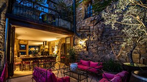 Une terrasse extérieure avec des murs en pierre, un coin repas et des meubles de couleur rose.