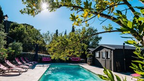 Une piscine avec des chaises longues, une terrasse en bois et un petit abri de jardin.
