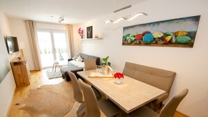 A modern living room with a dining area, a sofa, a coffee table, and a painting on the wall. - Finest Kitzblick Golf Suites TOP 2 (Zell am See)