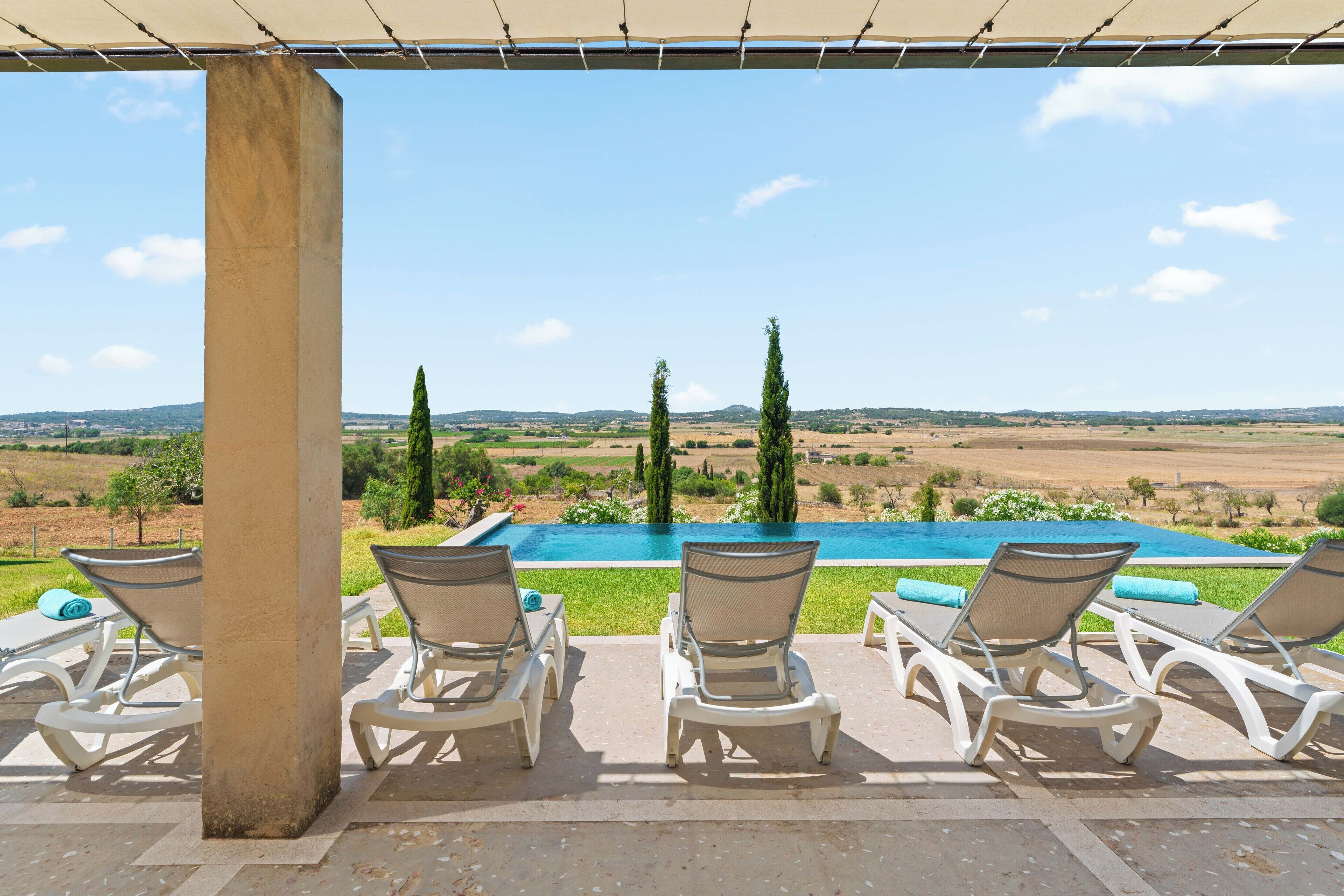 Zona junto a la piscina con sillones de descanso y vistas a la piscina y al paisaje.