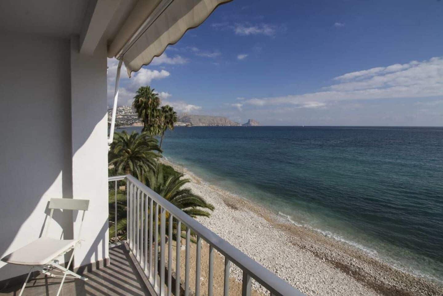 Un balcón con vistas a una playa de guijarros y al mar.