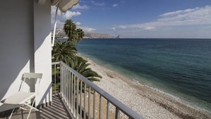 Ein Balkon mit Blick auf einen Kiesstrand und das Meer.