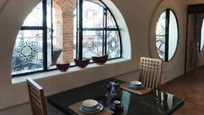 A dining area with a table set for two, a decorative vase, and a window with a brick wall view. - Spacious bright tiled 2 bedroom with Ocean View (Cerro)