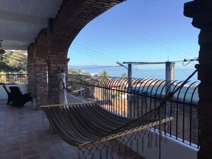 A balcony with a hammock, brick walls, and a view of the sea. - Spacious bright tiled 2 bedroom with Ocean View (Cerro)