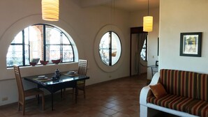 A dining area with a table and chairs, a sofa, and two large windows with decorative iron grilles. - Spacious bright tiled 2 bedroom with Ocean View (Cerro)