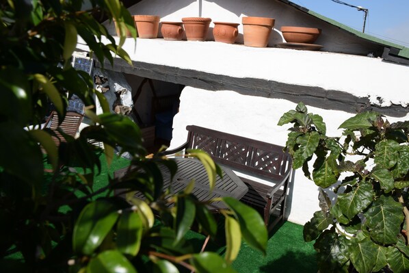 A patio area with a wooden bench, a white wall, and terracotta pots. - We look forward to you! (La Vega)