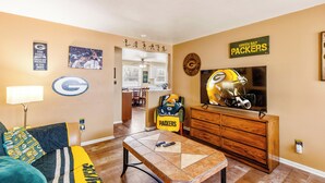 A living room with a TV, a couch, a coffee table, and a dining area.
