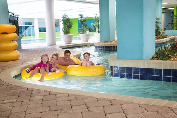 A pool area with a tiled edge, a brick floor, and a few potted plants.