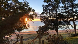 A wooden staircase leading to a beach with a view of the ocean and trees. - Stunning Bayfront Views (Hampton Bays)
