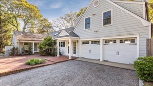 A two-story house with a garage, a covered porch, and a gravel driveway. - Stunning Bayfront Views (Hampton Bays)