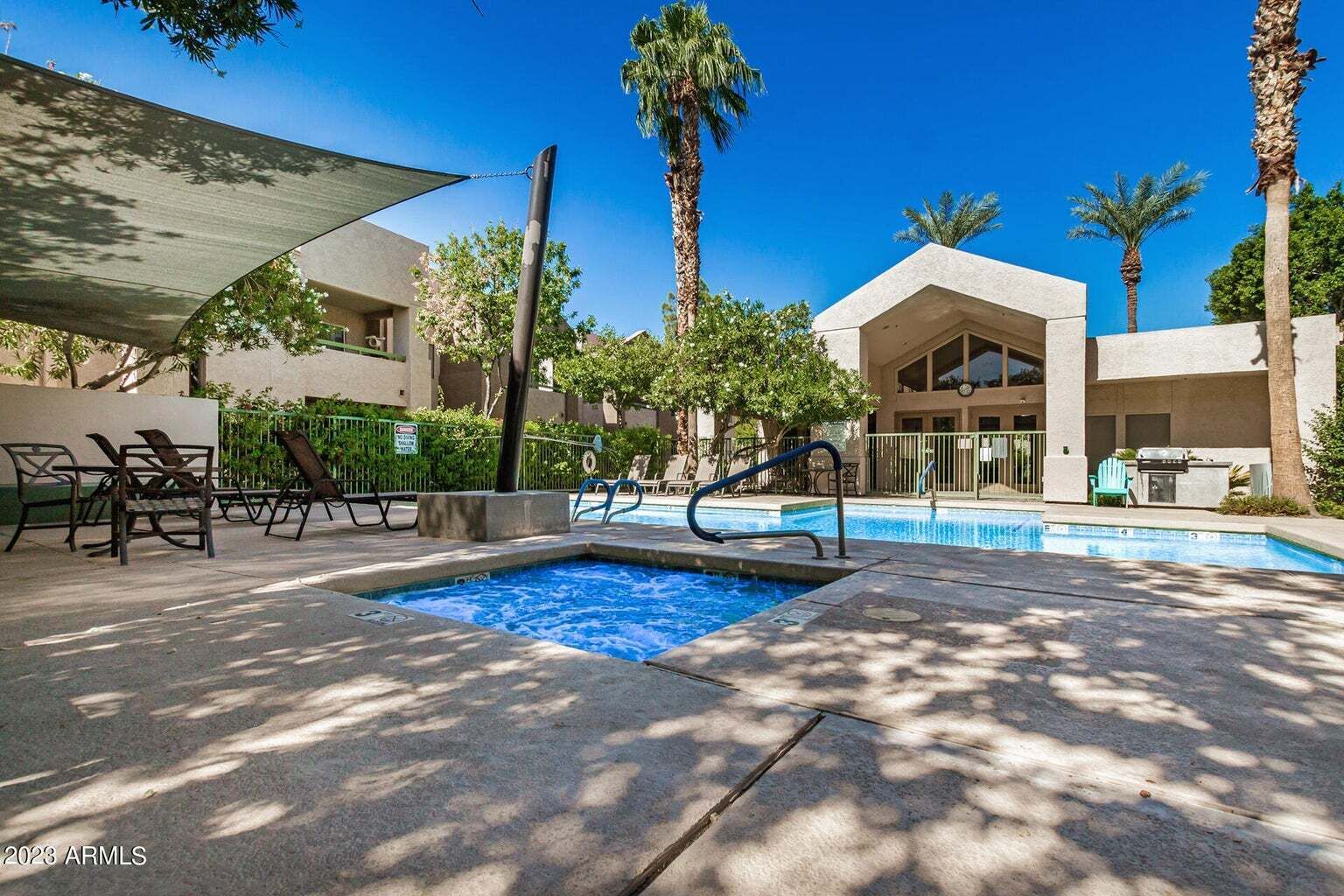 Zona de piscina con sillones reclinables, jacuzzi y palmeras.