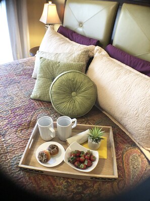 A neatly made breakfast tray on a bed with a patterned bedspread, pillows, and a headboard. - All the comforts of home in the Arizona sun! (Gilbert)
