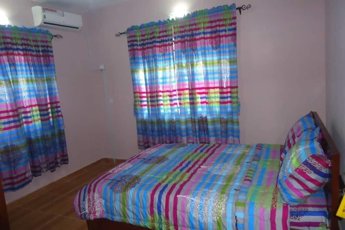 Un dormitorio con cama, cortinas y un equipo de aire acondicionado.