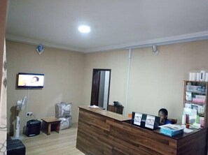 Guests can check in at the reception desk, where a flat-screen TV and comfortable seating area are available.