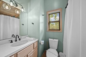 Bagno con lavandino, specchio, toilette e finestra con persiane.