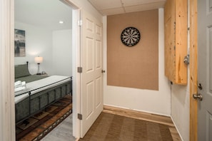 A room with a bed, a dartboard, and a wooden door.
