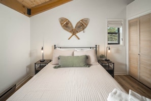 A bedroom with a bed, two bedside tables, a window, and a wardrobe.