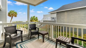 A covered outdoor area with a wooden bench, two wicker chairs, and a small table.