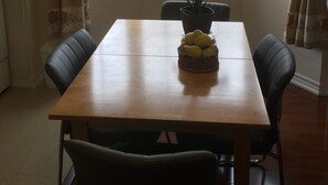 Un coin repas avec une table en bois et deux chaises, une plante en pot et un panier de fruits.