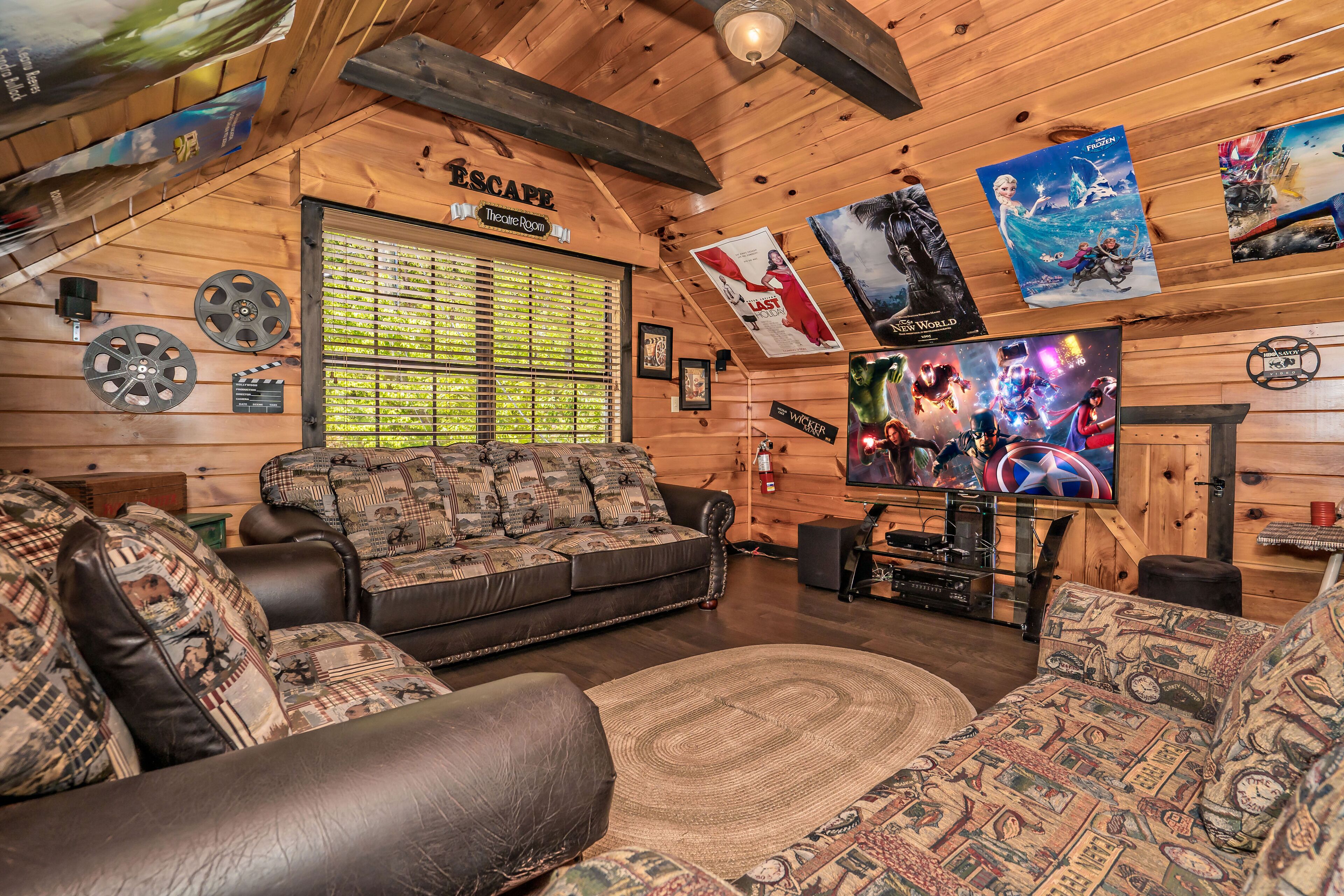 L’intérieur d’un chalet confortable, avec des murs en rondins, un canapé, un téléviseur et divers affiches.