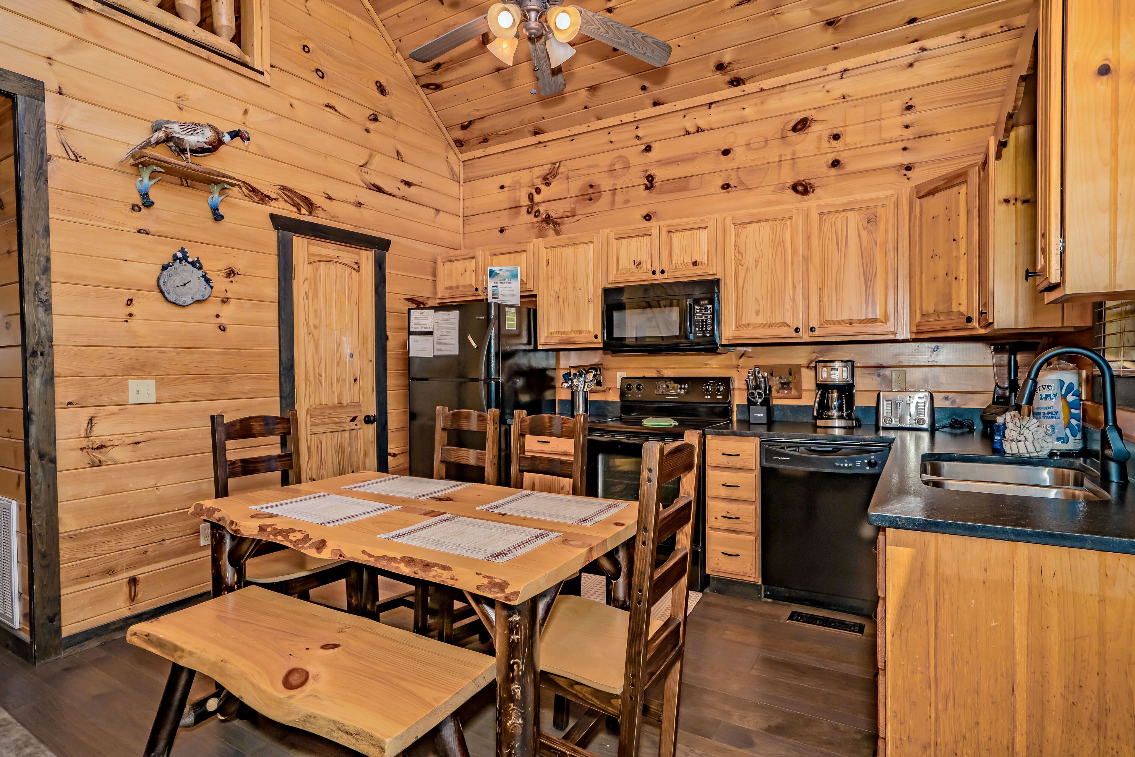Interior de una cabaña de madera con una mesa de comedor, sillas, refrigerador, microondas, cafetera y pileta.