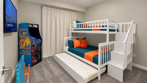A bunk bed with a mattress, pillows, and a play area with a game machine. - Sophisticated Holiday Condo, Only 7 min to Disney (Kissimmee)