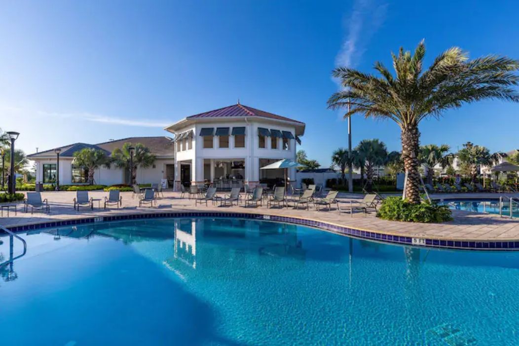 Un hotel con piscina, palmeras y sillas de descanso.