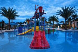 A water park with a red slide, blue and yellow play structures, and palm trees. - Sophisticated Condo, up to 6, Only 7 min to Disney (Kissimmee)