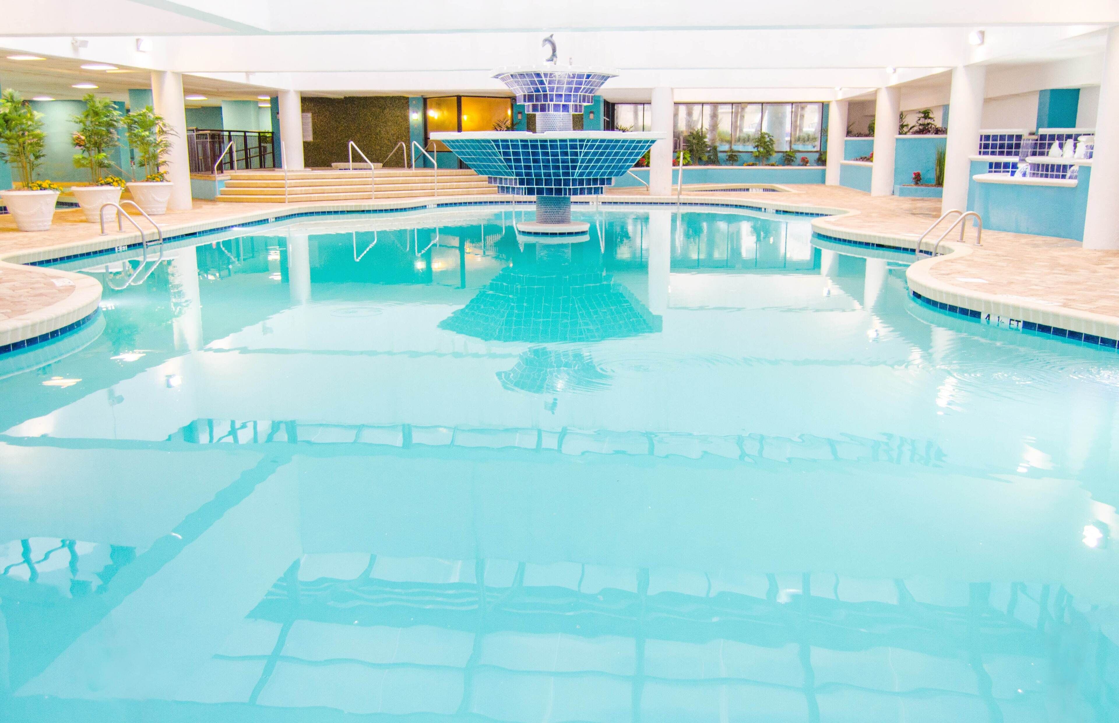 Une piscine intérieure dotée d’une fontaine centrale, de murs carrelés et d’un escalier menant à une zone d’observation.