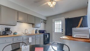 Una cocina moderna con armarios grises, encimera negra y una mesa de comedor con un letrero.