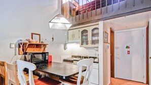 A compact kitchen with a dining area, white cabinets, and a small dining table with chairs. - (A203) Loft Condominiums (Yosemite National Park)