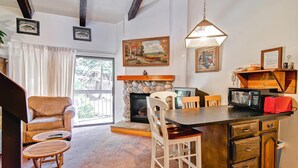 A cozy living room with a fireplace, a dining area, and a kitchen with a microwave and toaster. - (A203) Loft Condominiums (Yosemite National Park)