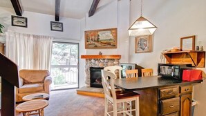 A cozy living room with a fireplace, a dining area with a stone fireplace, and a kitchen with a microwave and toaster. - (A203) Loft Condominiums (Yosemite National Park)