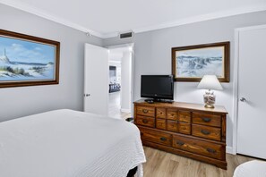 Ett hotellrum med en säng, en byrå, en tv och två tavlor på väggarna.