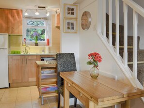 A kitchen with wooden cabinets, a dining table, and a vase with flowers. - 2 bedroom accommodation in Ambleside (Ambleside)