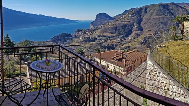 Ein Balkon mit Tisch und Stühlen, der einen schönen Blick auf einen See und Berge bietet.
