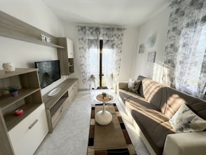 Una sala de estar moderna con sofá, televisión y una mesa de centro.