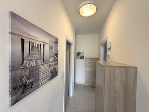 Un pasillo con un armario de madera, un banco y una pared con un diseño geométrico.