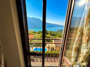 Een balkon met uitzicht op een meer, bergen en groen.