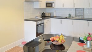 A modern kitchen with white cabinets, a microwave, a stove, and a sink. - Dove Cottage - UK3284 (Acklington, near Amble)