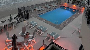 Un espace aménagé au bord de la piscine, avec des chaises longues et une piscine, offrant une vue sur l’océan.