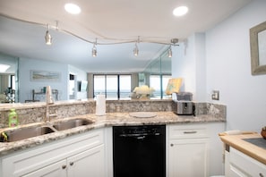 A kitchen with a granite countertop, stainless steel sink, and a dishwasher.