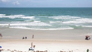 Une plage avec des gens, un bateau et un parasol de plage.